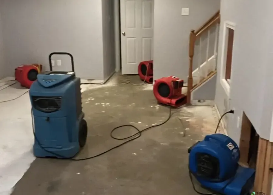 Dehumidifier and air movers drying a hallway beside a staircase