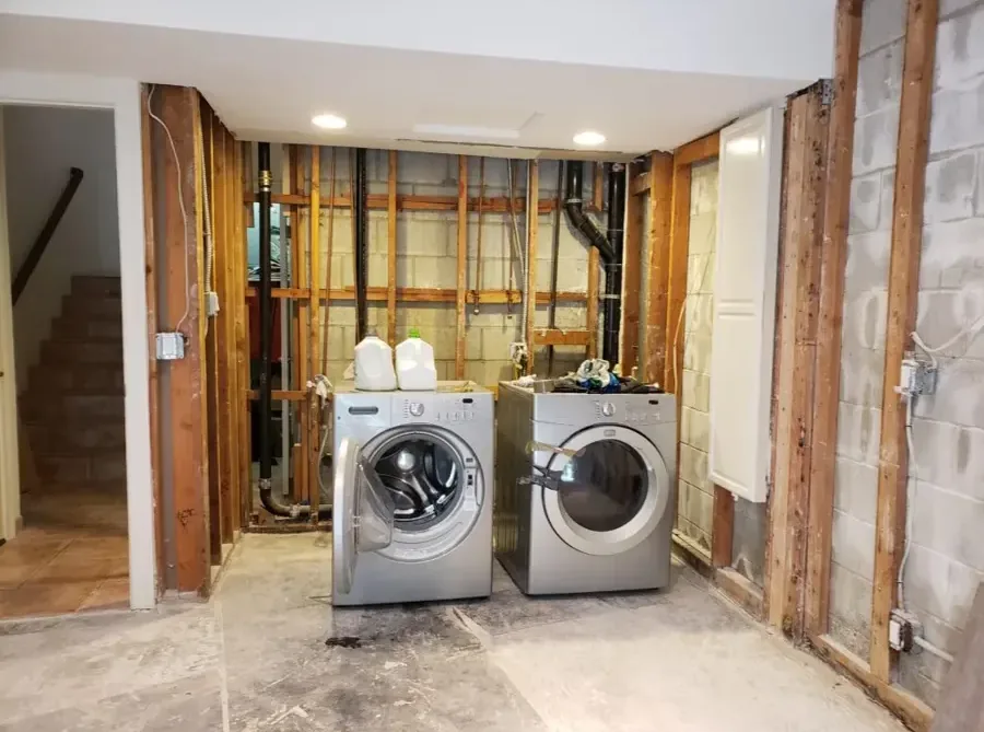 A basement laundry area with the walls opened after an appliance leak