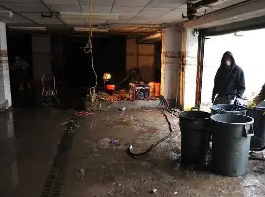 A crew hauling out floodwater debris from a ground floor after a storm