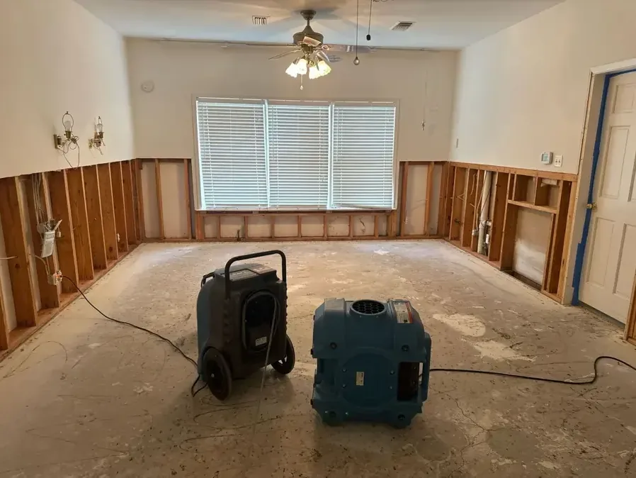 A dehumidifier and an air mover drying a room after a drywall flood cut